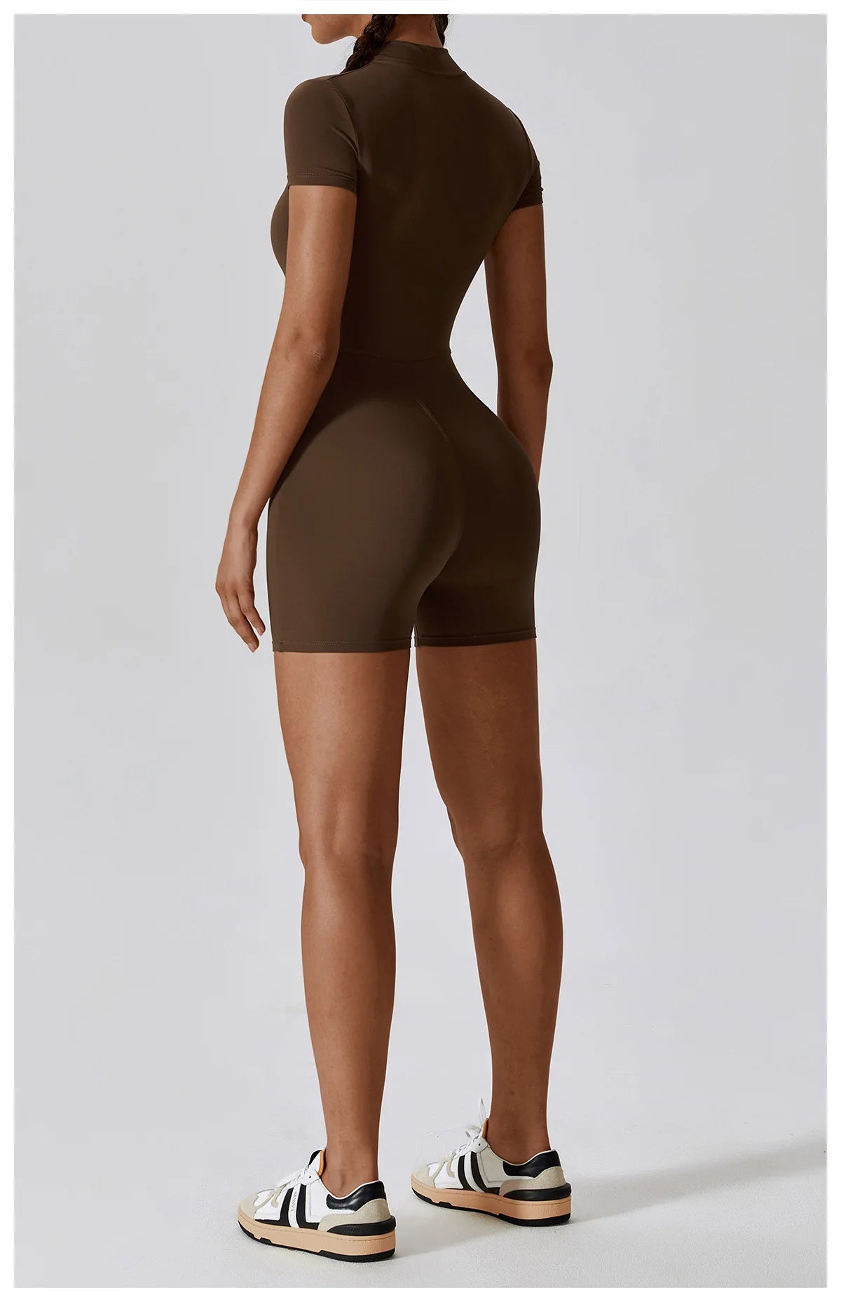 Person wearing a brown bodysuit on a light gray background