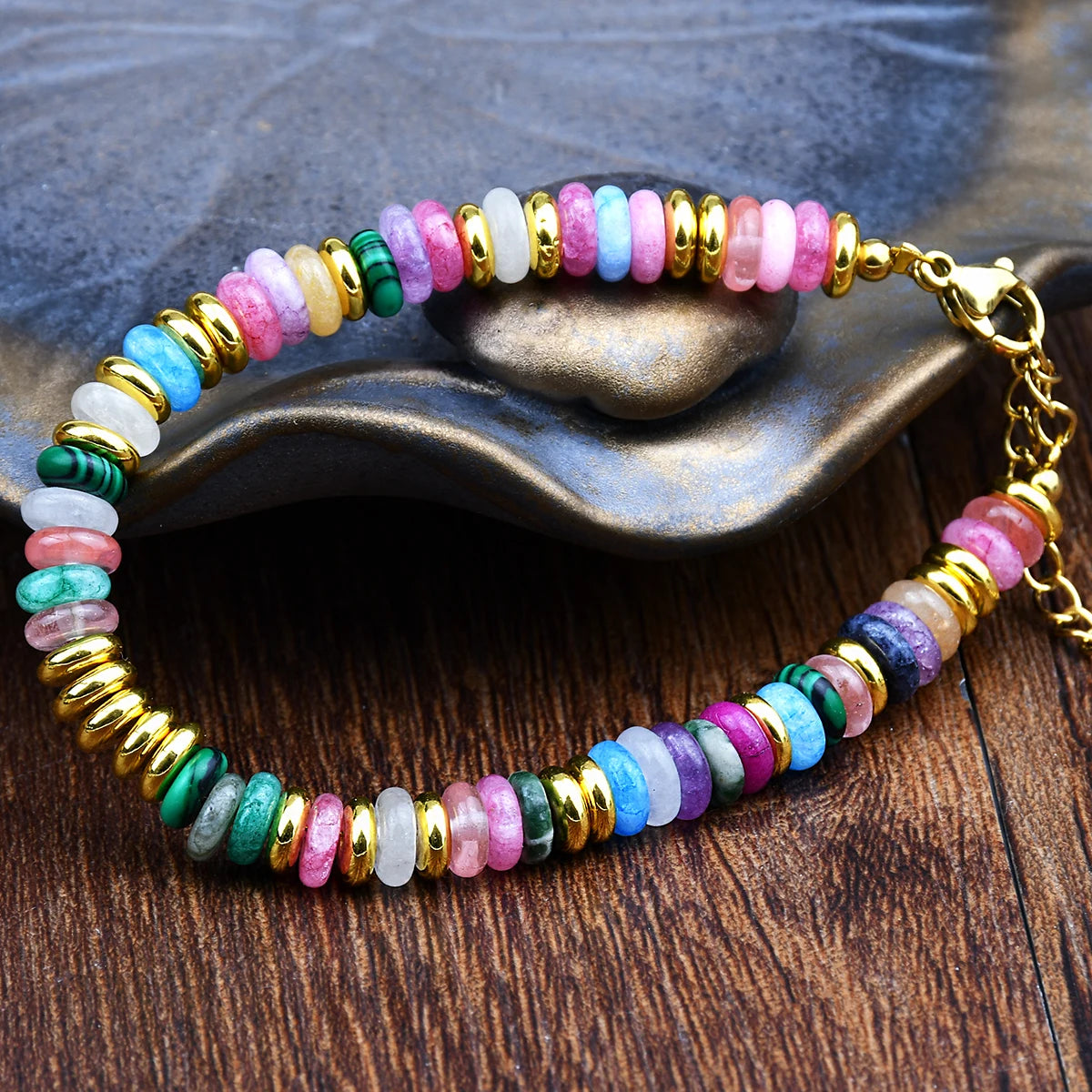 Multicolored beaded bracelet with gold accents on a wooden surface