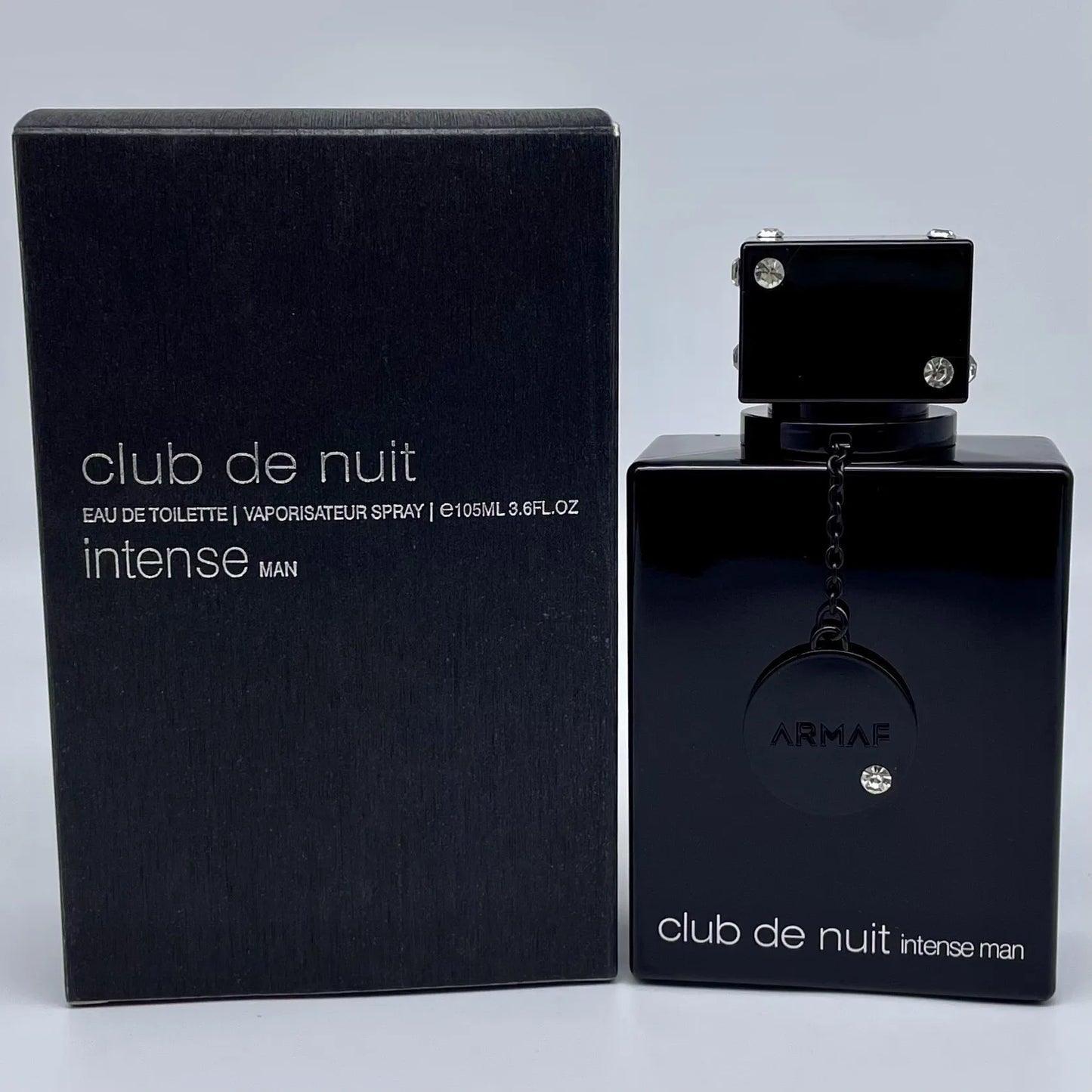 Black Armaf Club de Nuit intense man perfume bottle and packaging on a light gray background