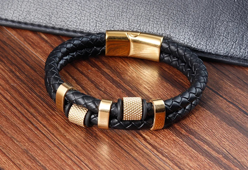 Black braided leather bracelet with gold accents on a wooden surface
