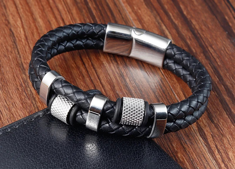 Black braided leather bracelet with silver metal accents on a wooden surface