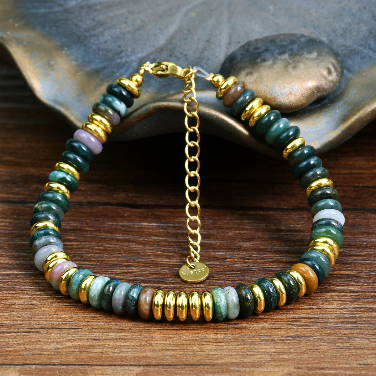 Beaded bracelet with gold chain on a wooden surface