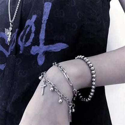 Silver jewelry including a bracelet and necklace on a person wearing a black garment with blue designs.