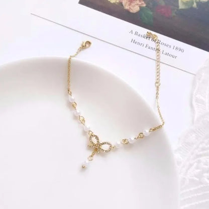 Gold necklace with bow charm on a white dish