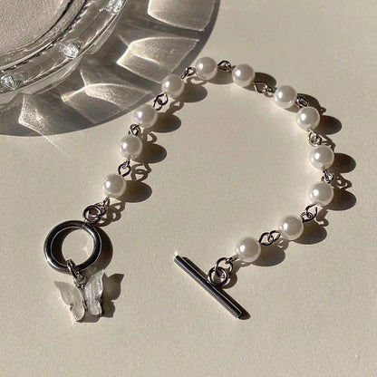 Pearl bracelet with silver charms on a light surface