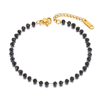 Black beaded bracelet with gold clasp on a white background