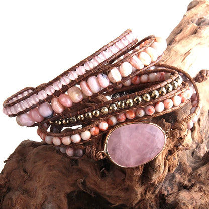 Multistrand beaded bracelet with a large pink stone on a wooden surface