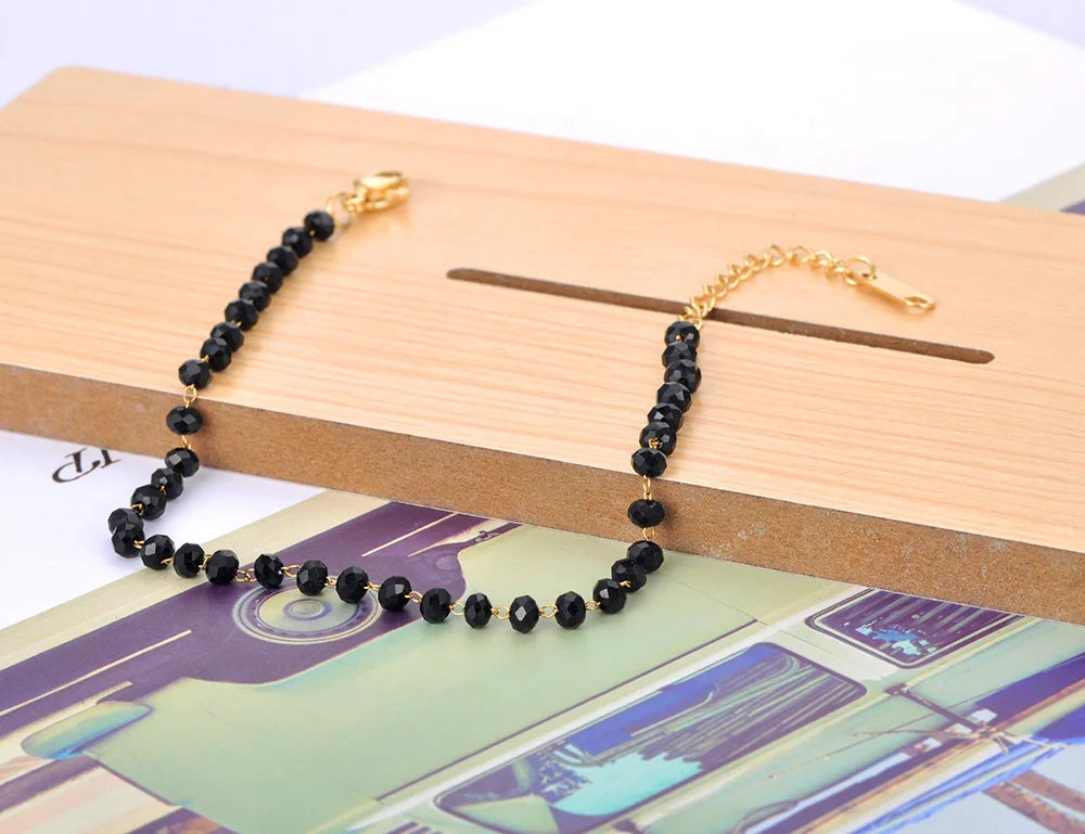 Black beaded bracelet with gold clasp on a wooden surface