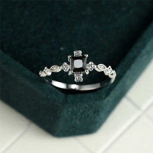 Silver ring with a black gemstone on a dark green cushion