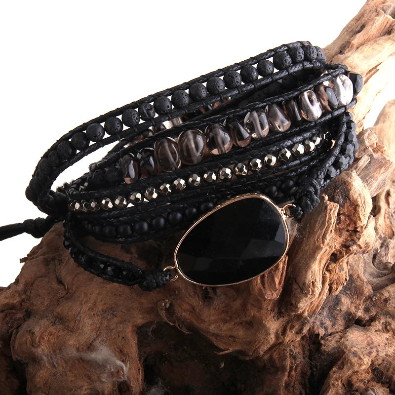 Black beaded wrap bracelet with a large black stone on a wooden surface