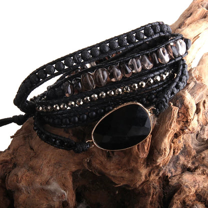 Black beaded wrap bracelet with a large black stone on a wooden surface