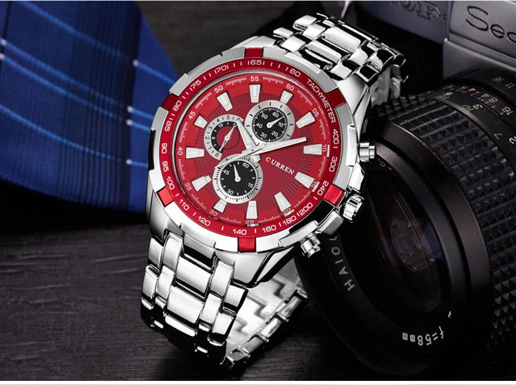 Wristwatch with red face and silver metal strap on a blurred background