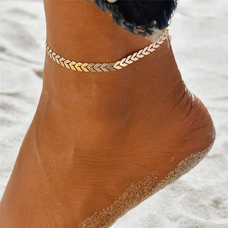 Gold anklet on a foot with sand in the background