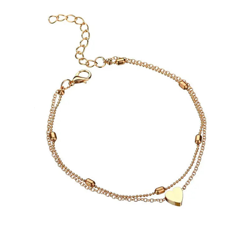 Gold bracelet with heart charm on a white background