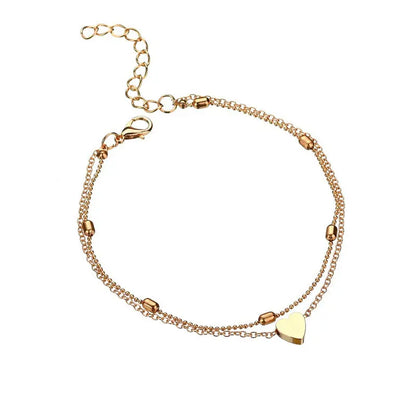 Gold bracelet with heart charm on a white background