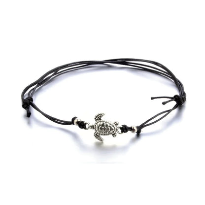 Black cord bracelet with a turtle charm on a white background