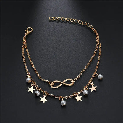 Gold chain necklace with star and pearl charms on a black background