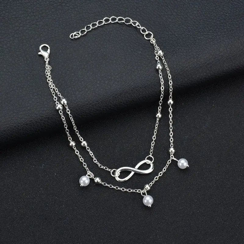 Silver bracelet with infinity symbol and beads on a dark fabric background