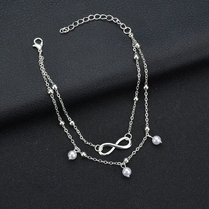 Silver bracelet with infinity symbol and beads on a dark fabric background