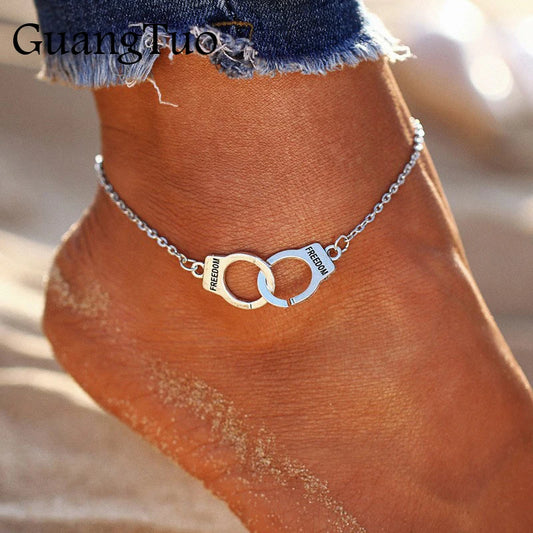 Ankle bracelet with interlocking rings and 'freedom' text on a person's ankle.