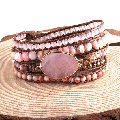Multistrand bracelet with pink stone and brown leather strap on wooden surface
