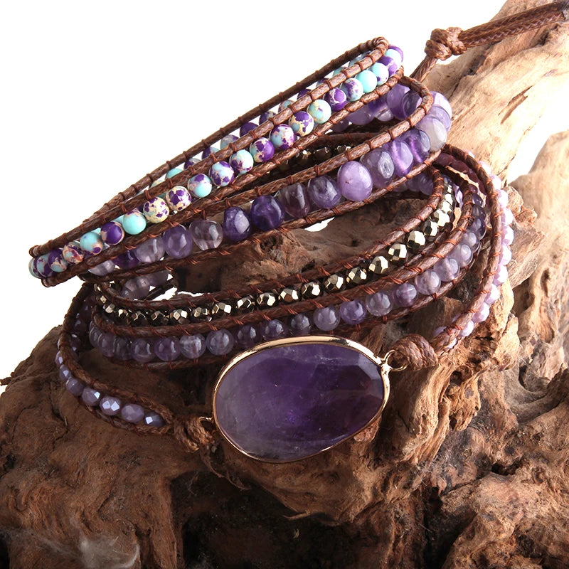 Stack of beaded bracelets with a prominent purple stone on a wooden surface