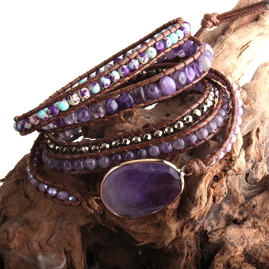 Stack of beaded bracelets with a prominent purple stone on a wooden surface