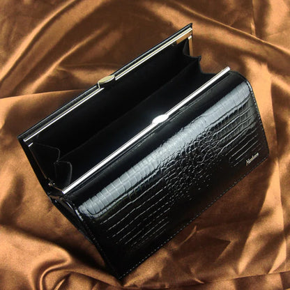 Black crocodile-patterned clutch bag on a brown fabric background
