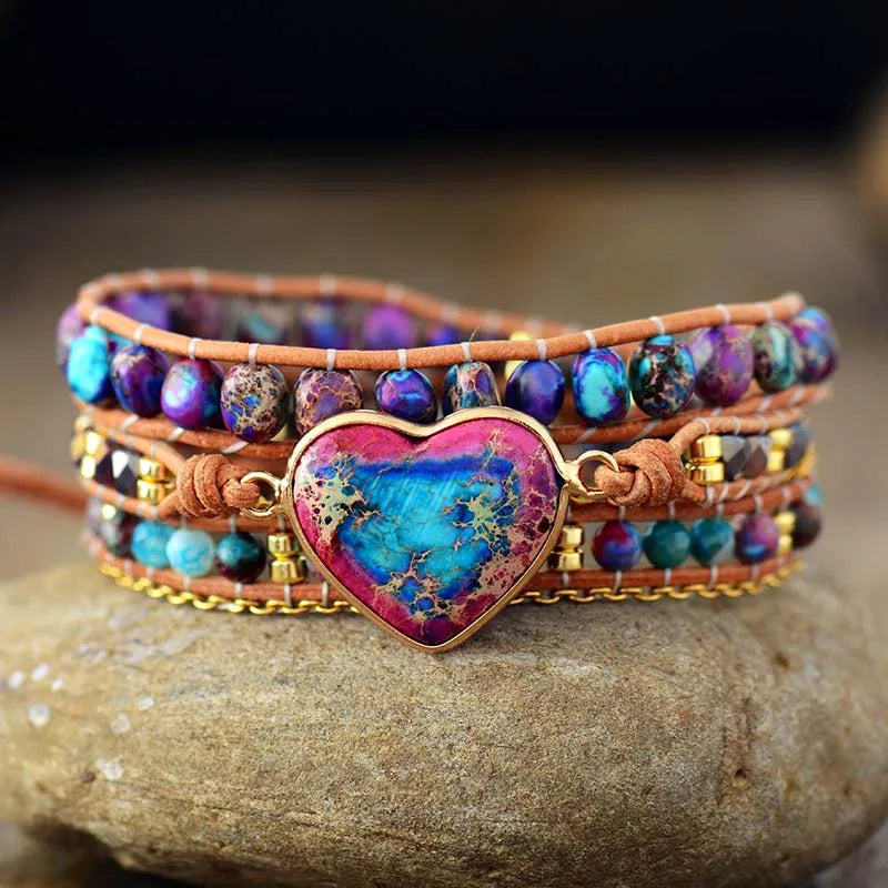 Multicolored beaded bracelet with a heart-shaped charm on a stone surface