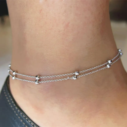 Silver anklets on a person's ankle with a blurred background
