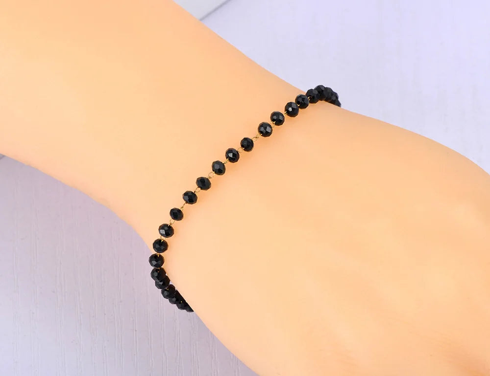 Black beaded bracelet on a wrist against a neutral background