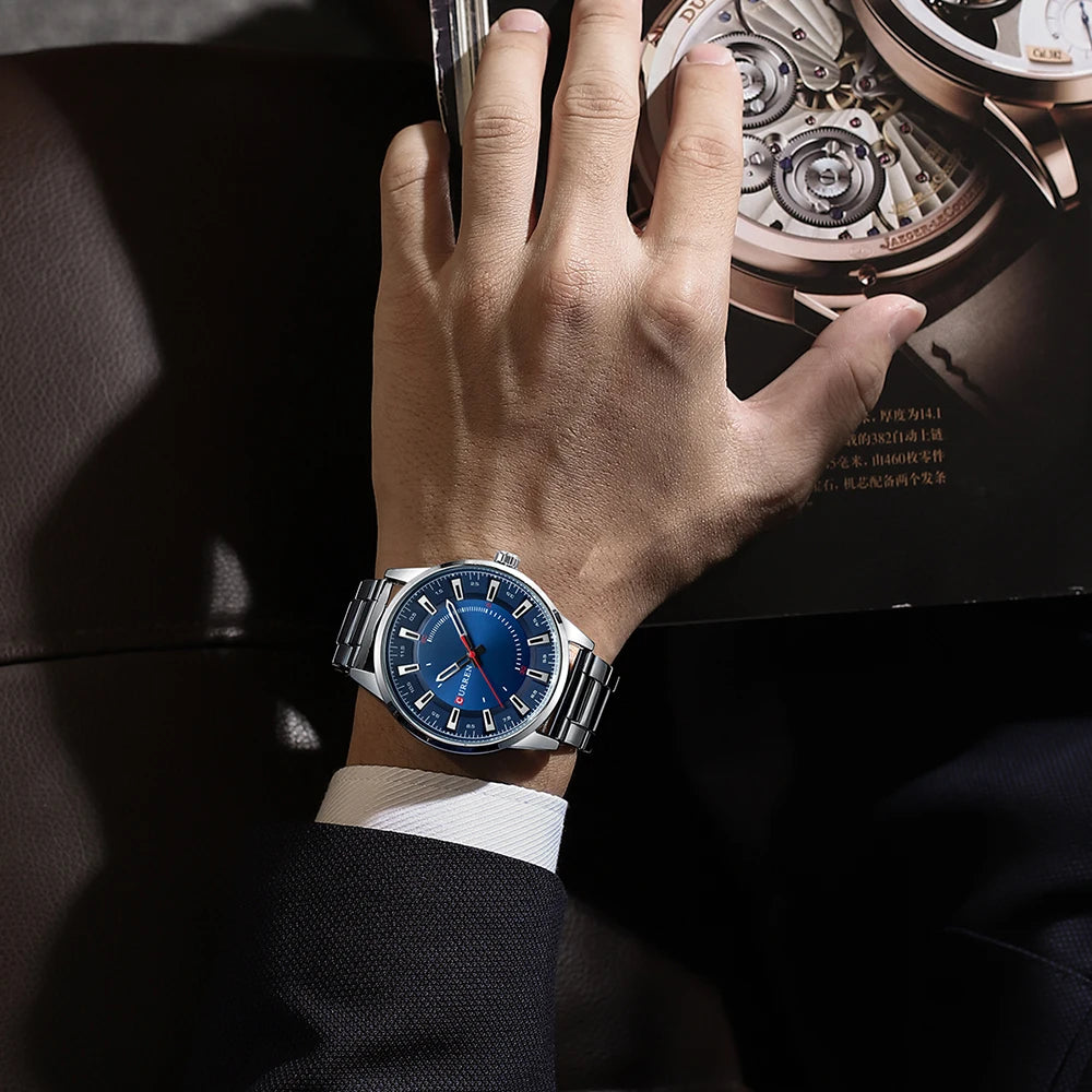 Hand wearing a blue watch with a mechanical component in the background