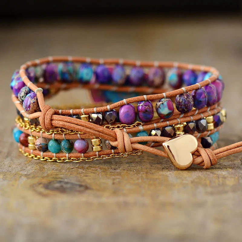 Multicolored beaded bracelet with leather wrap and heart charm on a wooden surface