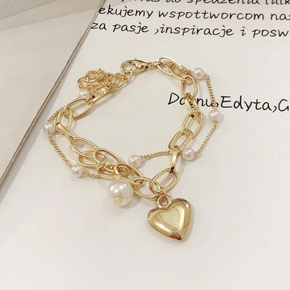 Gold bracelet with heart charm and pearls on a light background