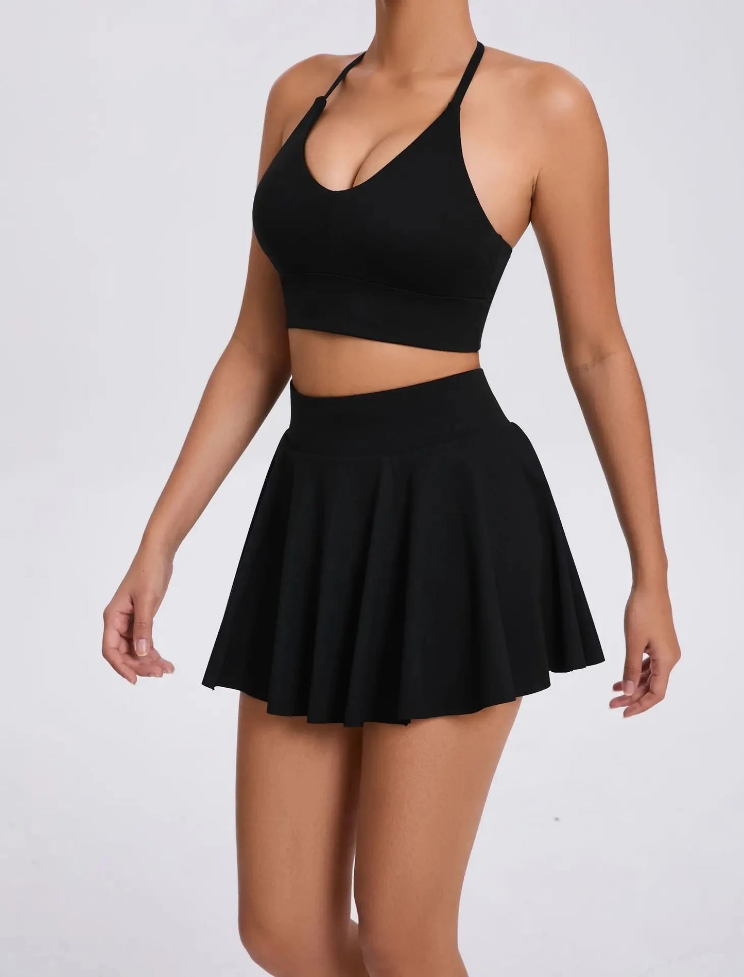 Person wearing a black crop top and skirt on a white background