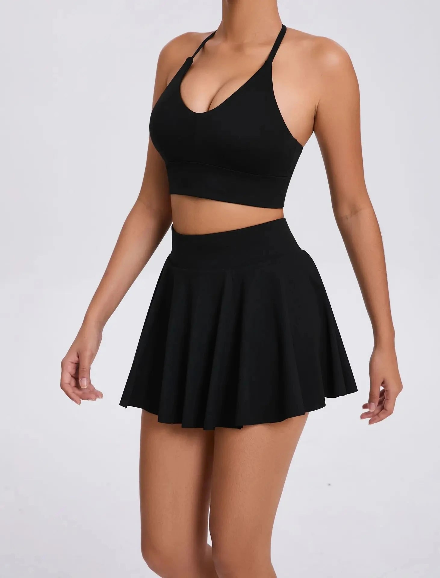 Person wearing a black crop top and skirt on a white background