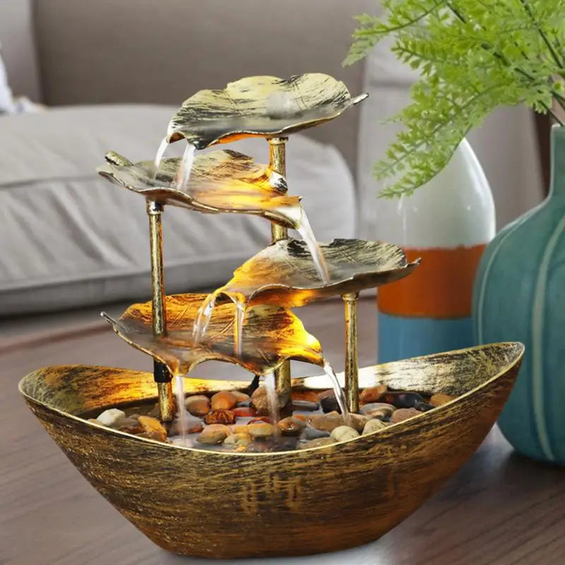 Decorative indoor water fountain with leaf design on a table.