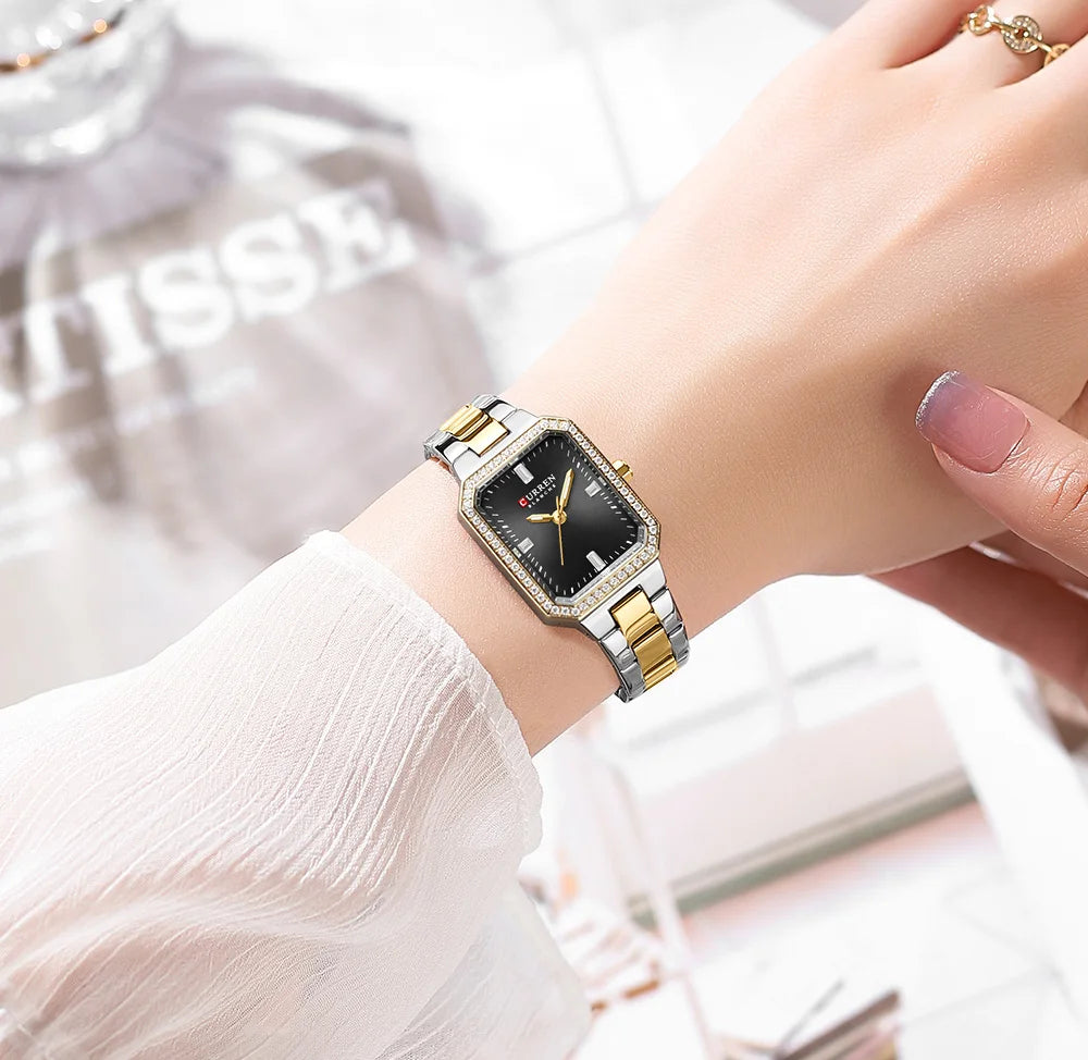 Gold and silver watch on a wrist with a blurred background