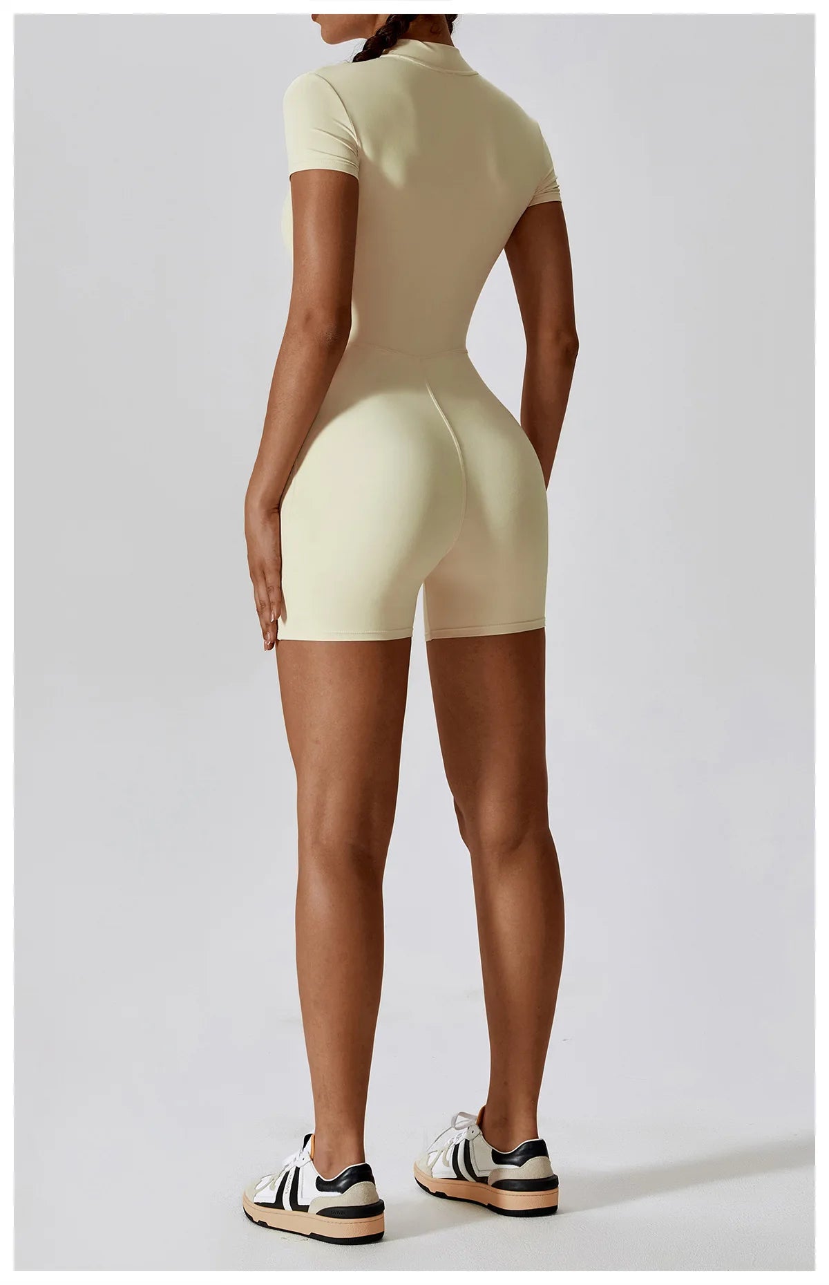Person wearing a beige bodysuit against a white background