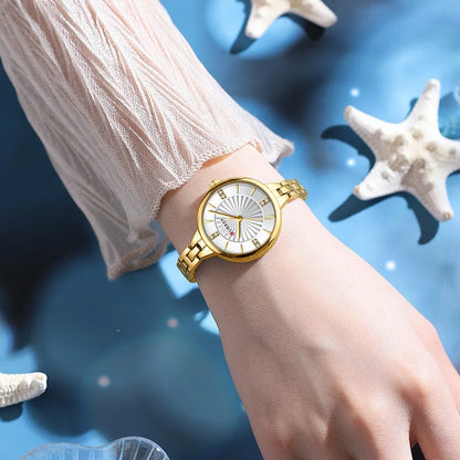 Gold wristwatch on a wrist with a blue background featuring starfish and shells