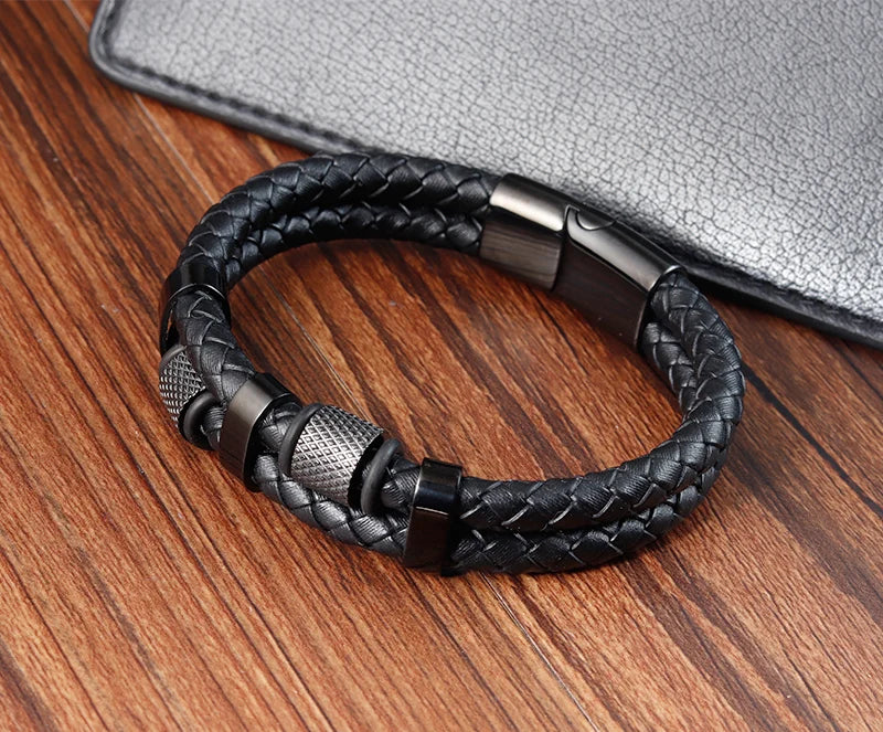 Black braided leather bracelet with metal clasp on a wooden surface