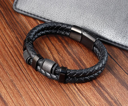 Black braided leather bracelet with metal clasp on a wooden surface
