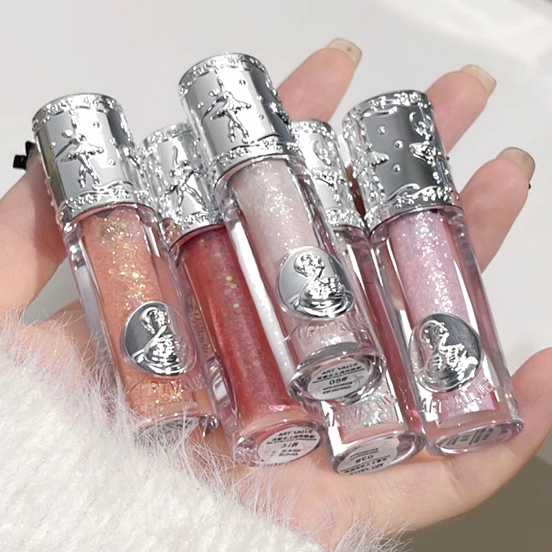 Four lip glosses with silver caps held in a hand against a white background