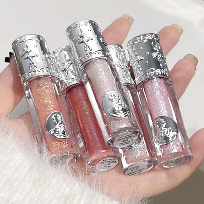 Four lip glosses with silver caps held in a hand against a white background