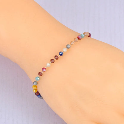 Multicolored beaded bracelet on a wrist against a light background
