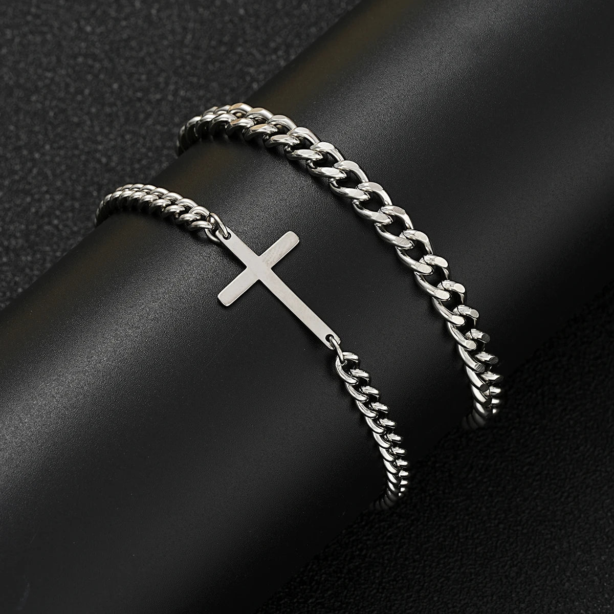 Silver chain bracelet with a cross on a dark surface