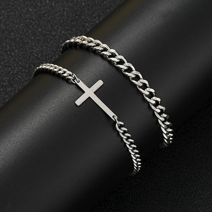 Silver chain bracelet with a cross on a dark surface