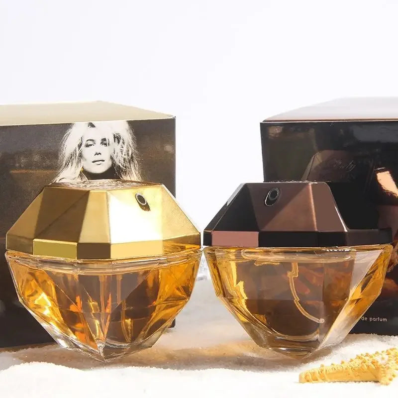 Two gold perfume bottles with packaging in the background