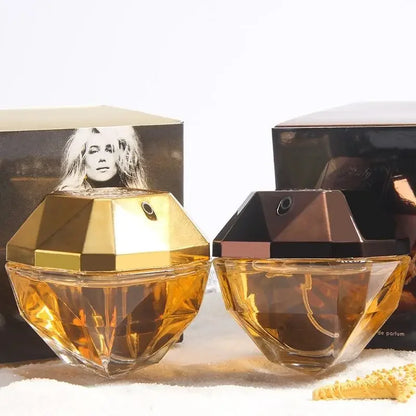 Two gold perfume bottles with packaging in the background