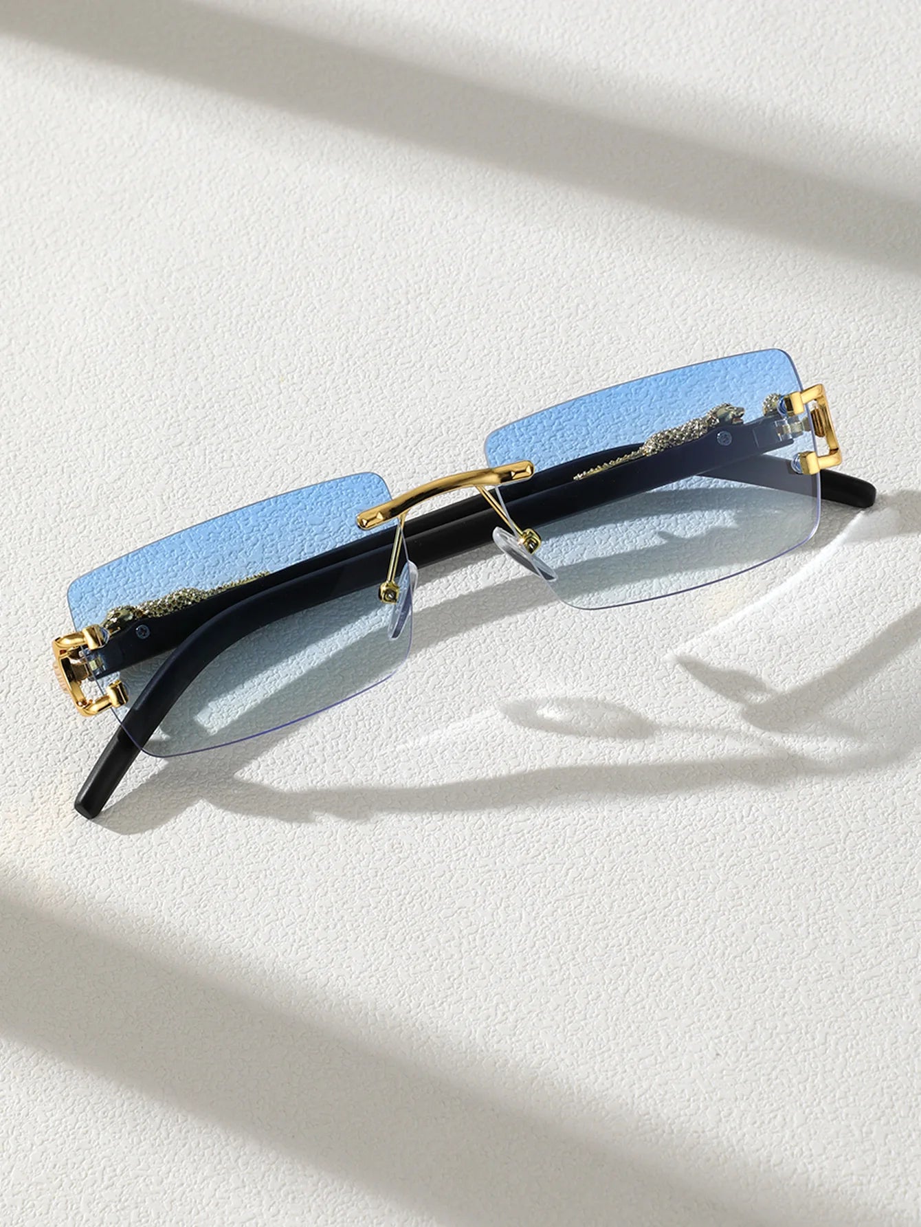 Sunglasses with blue lenses and gold frames on a white surface